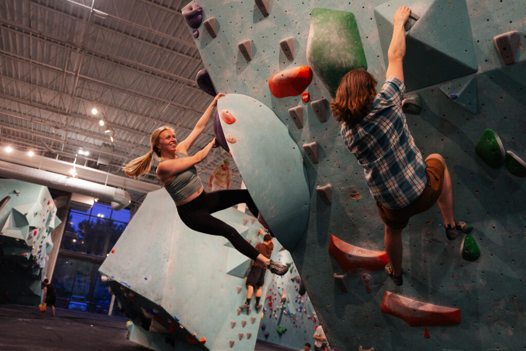 Minneapolis Bouldering Project engagement session with couple hanging from a boulder wall