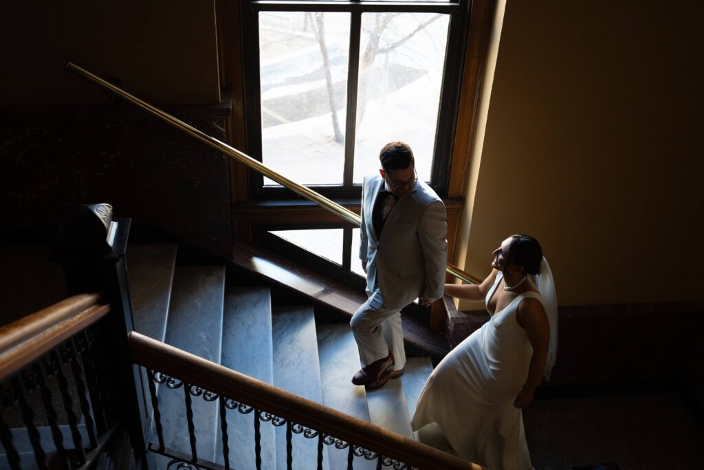 Bride and groom walking up the stairs of the Landmark Center, in Saint Paul, Minnesota